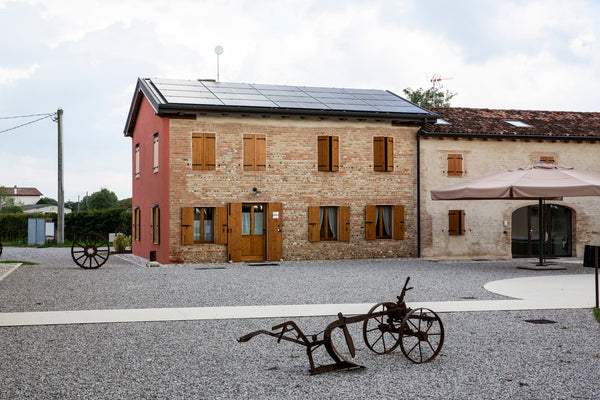 Gästehaus und Büro des Weinguts Case Paolin mit alten Weinbergsgeräten, die den Innenhof verschönern.