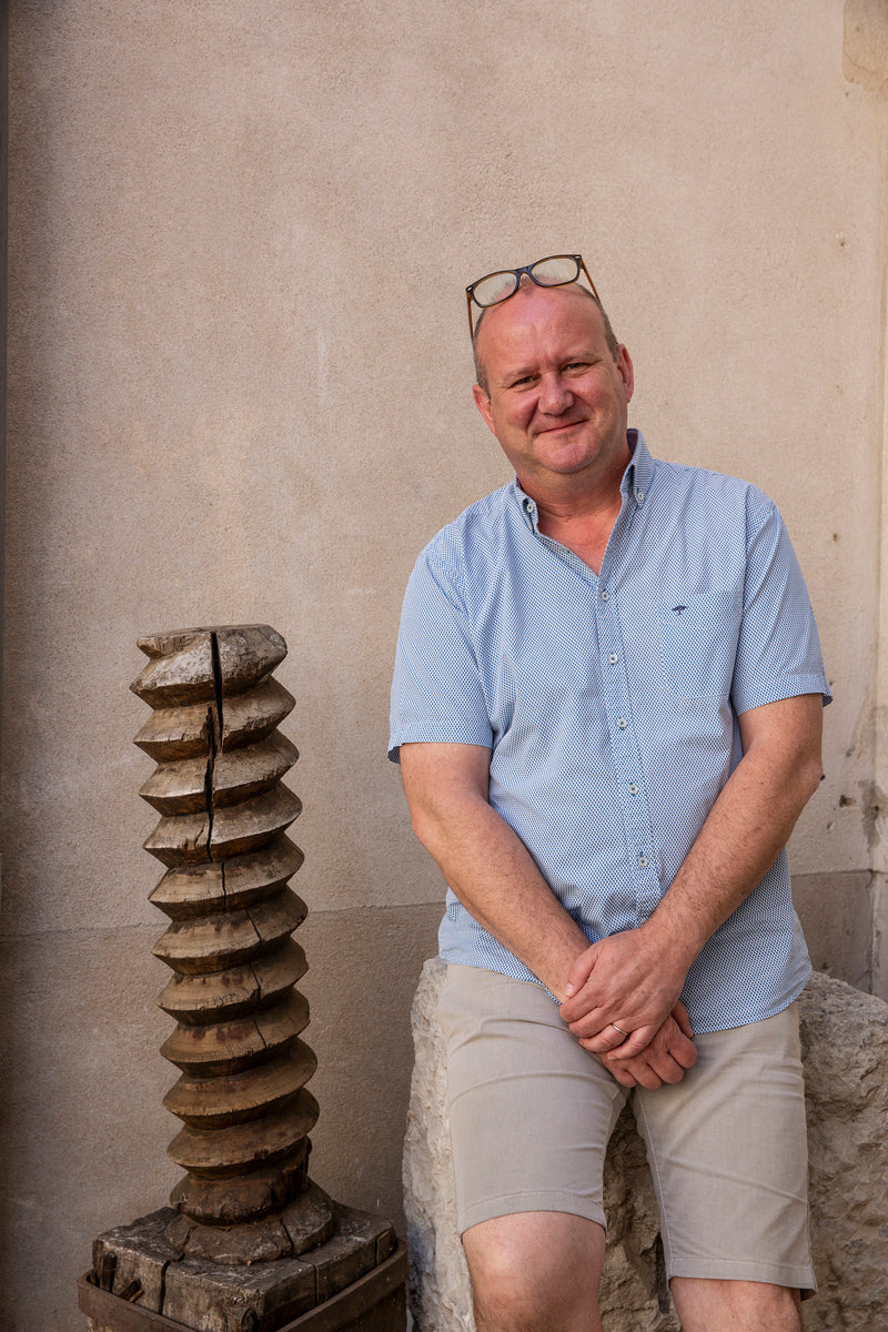 Portrait von Lionel Fraisse vom Weingut Domaine Alain Voge neben einer großen Holzschraube.