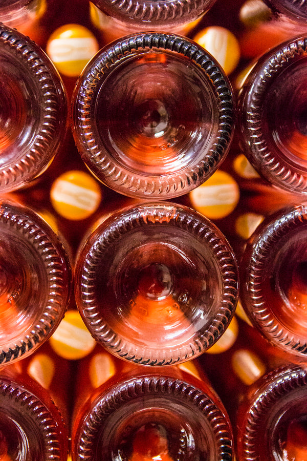 Foto von gestapelten Rosé-Schaumweinflaschen. Man sieht nur die Flaschenböden.