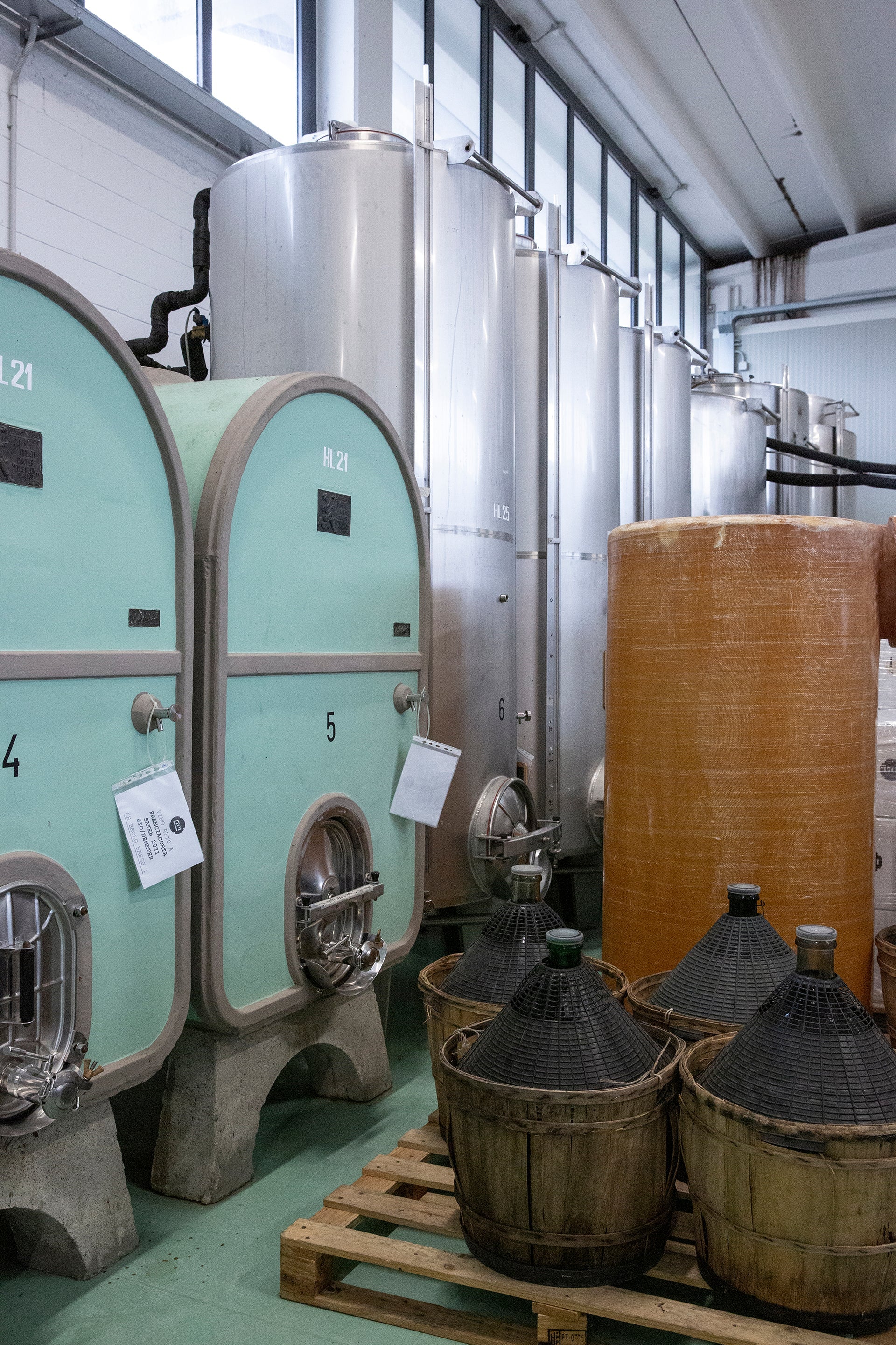 Kellerei mit Edelstahl- und Zementtanks sowie Glasballoons auf Paletten im Franciacorta-Weingut von Silvia und Federico Stefini