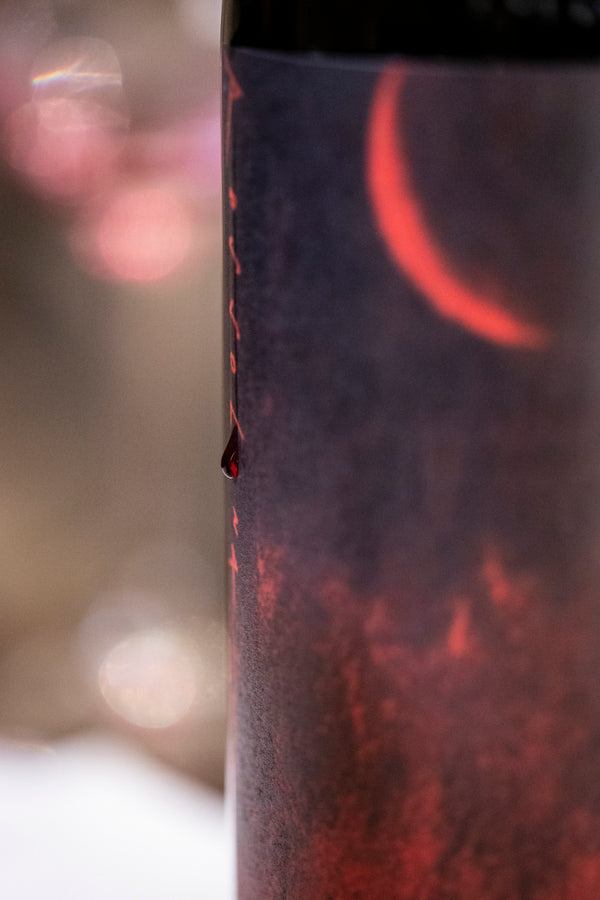 Ein Tropfen Rotwein läuft an einer Flasche herunter