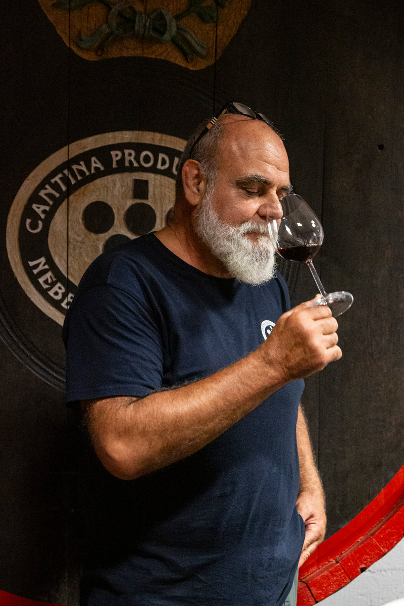 Portrait des Leiters der Cantina di Carema, der an einem Glas Rotwein riecht.