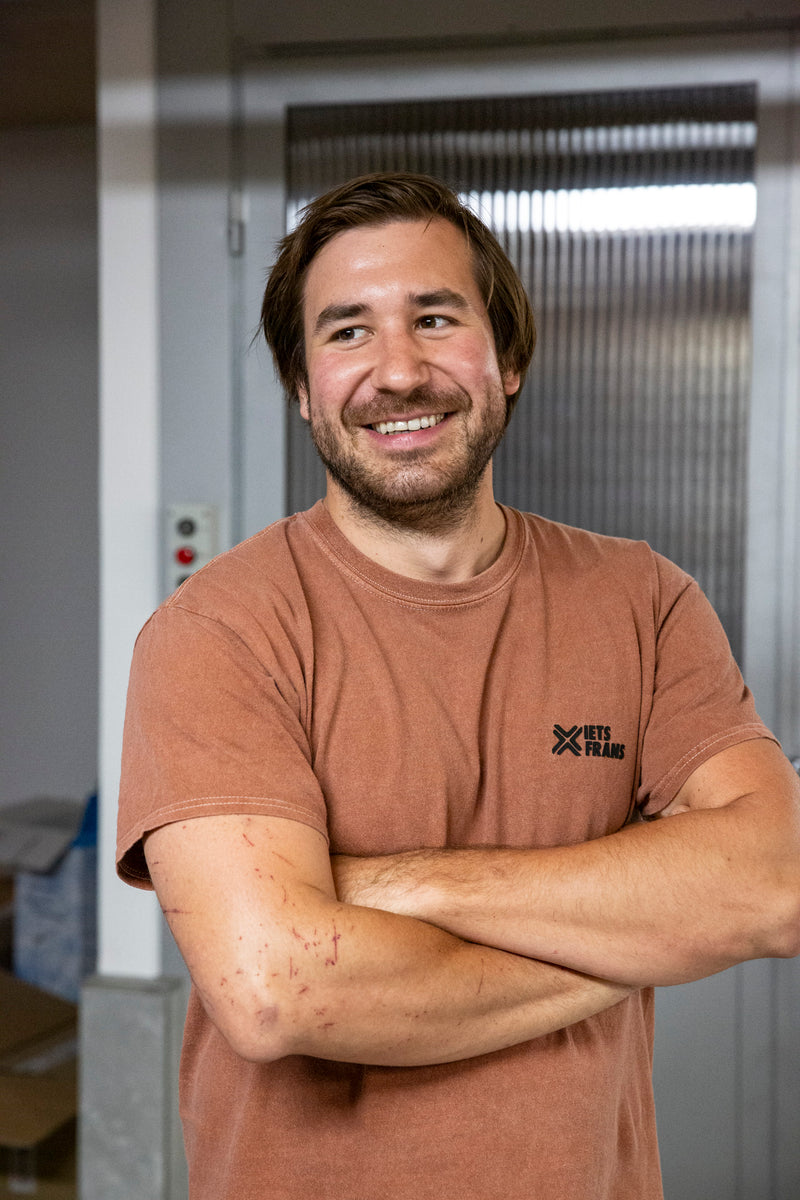 Portrait von Stefan Wellanschitz, der fröhlich lacht, mit einem zerkratzten Arm von der Arbeit im Weinberg.